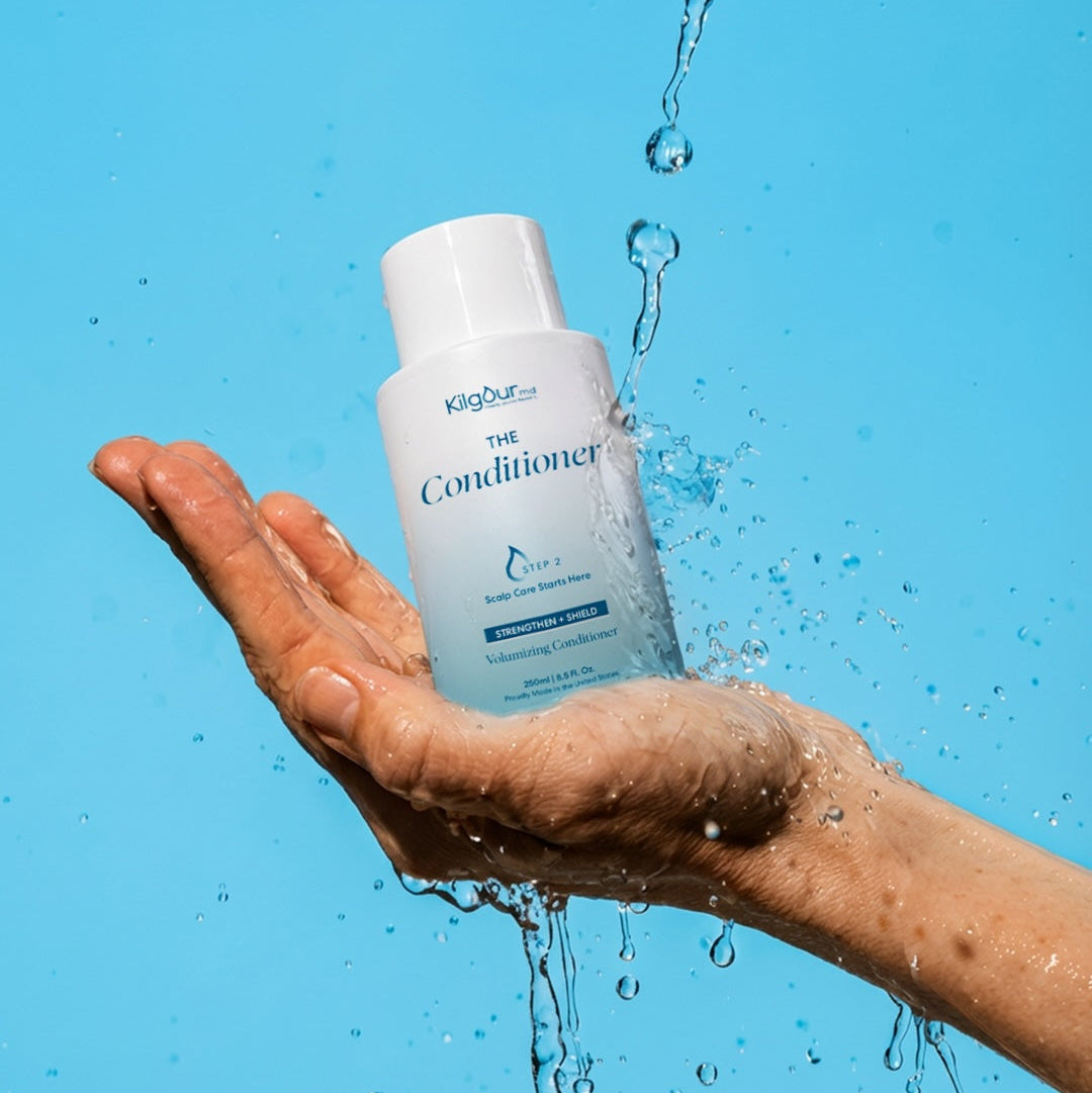 Hand holding a bottle of 'The Conditioner' with water droplets against a blue background