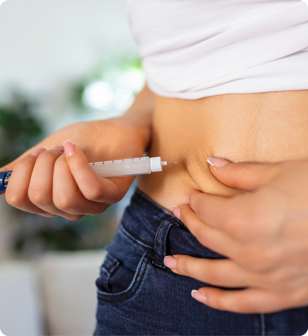 Close-up of a person injecting a subcutaneous medication into their lower abdomen with an auto-injector pen