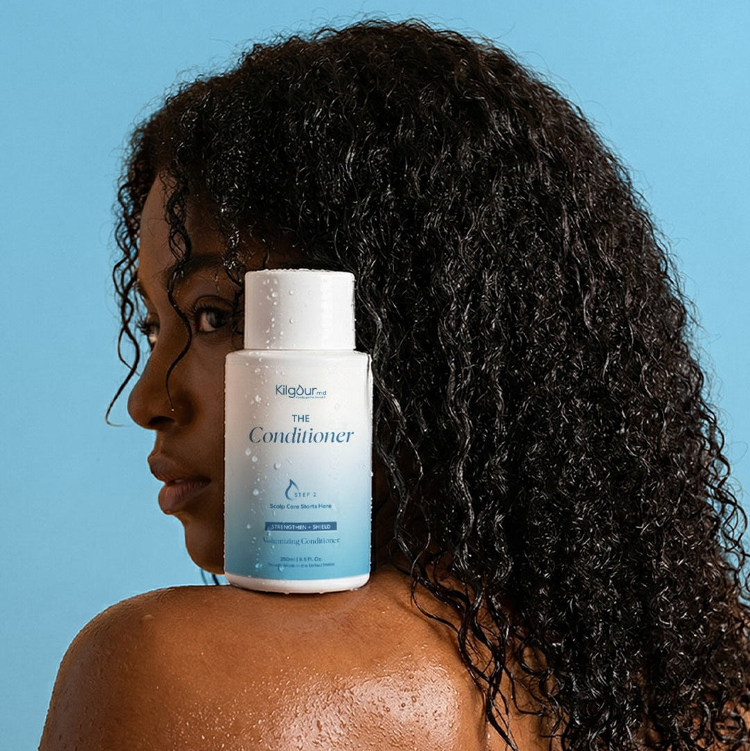 KilgourMD The Conditioner bottle on shoulder of woman with wet curly dark hair, blue background