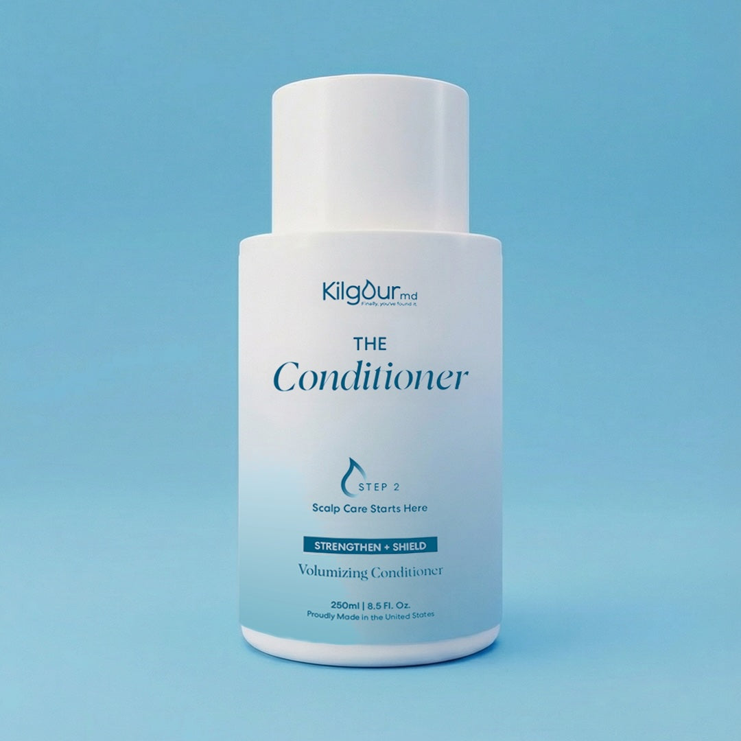 Front view of The Conditioner bottle showing white pump-top, minimalist label, on light blue background