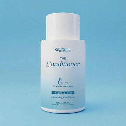 Front view of The Conditioner bottle showing white pump-top, minimalist label, on light blue background