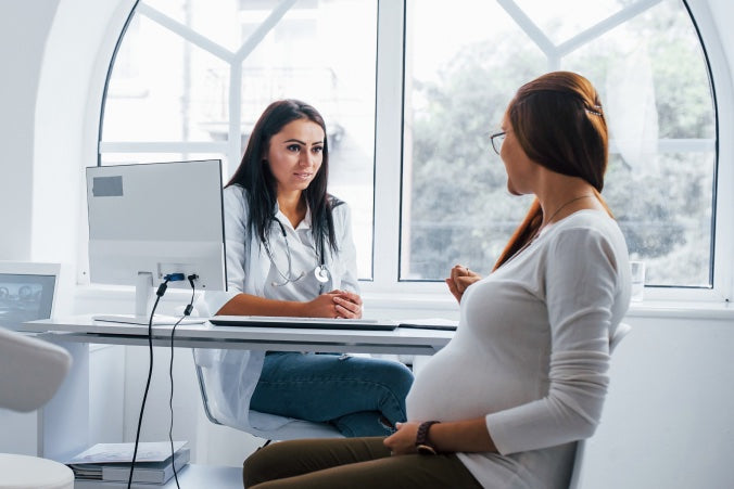 Pregnant woman speaking with a doctor in a bright medical office