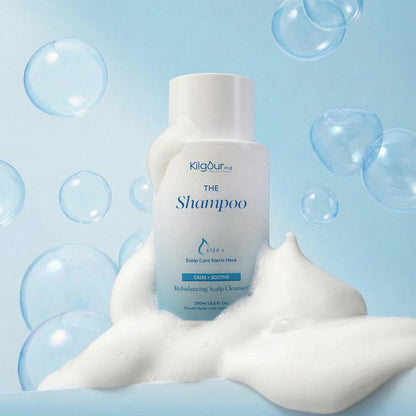 Front view of The Shampoo (Calm + Soothe) bottle showing foamy lather and floating bubbles on a light blue background
